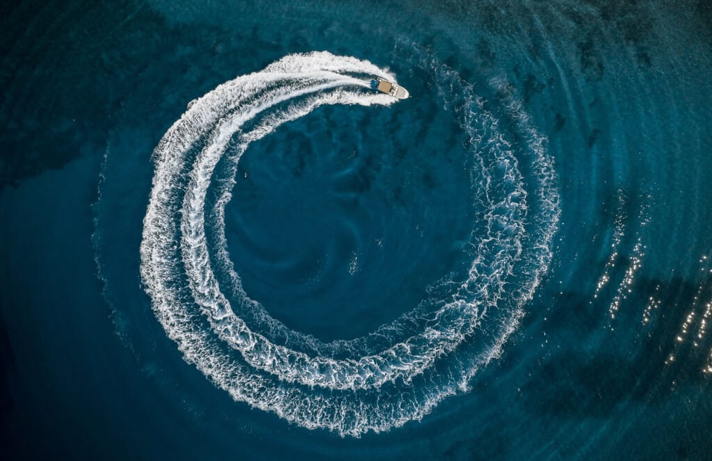 Speed boat in mediterranean sea making a cyrcle from bubbles, aerial view