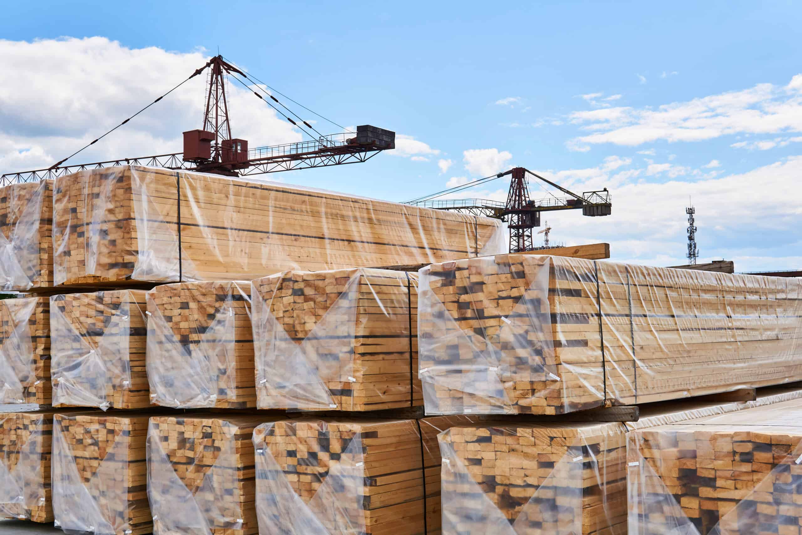 packaged freshly made boards and cranes in the background in the yard of the woodworking production