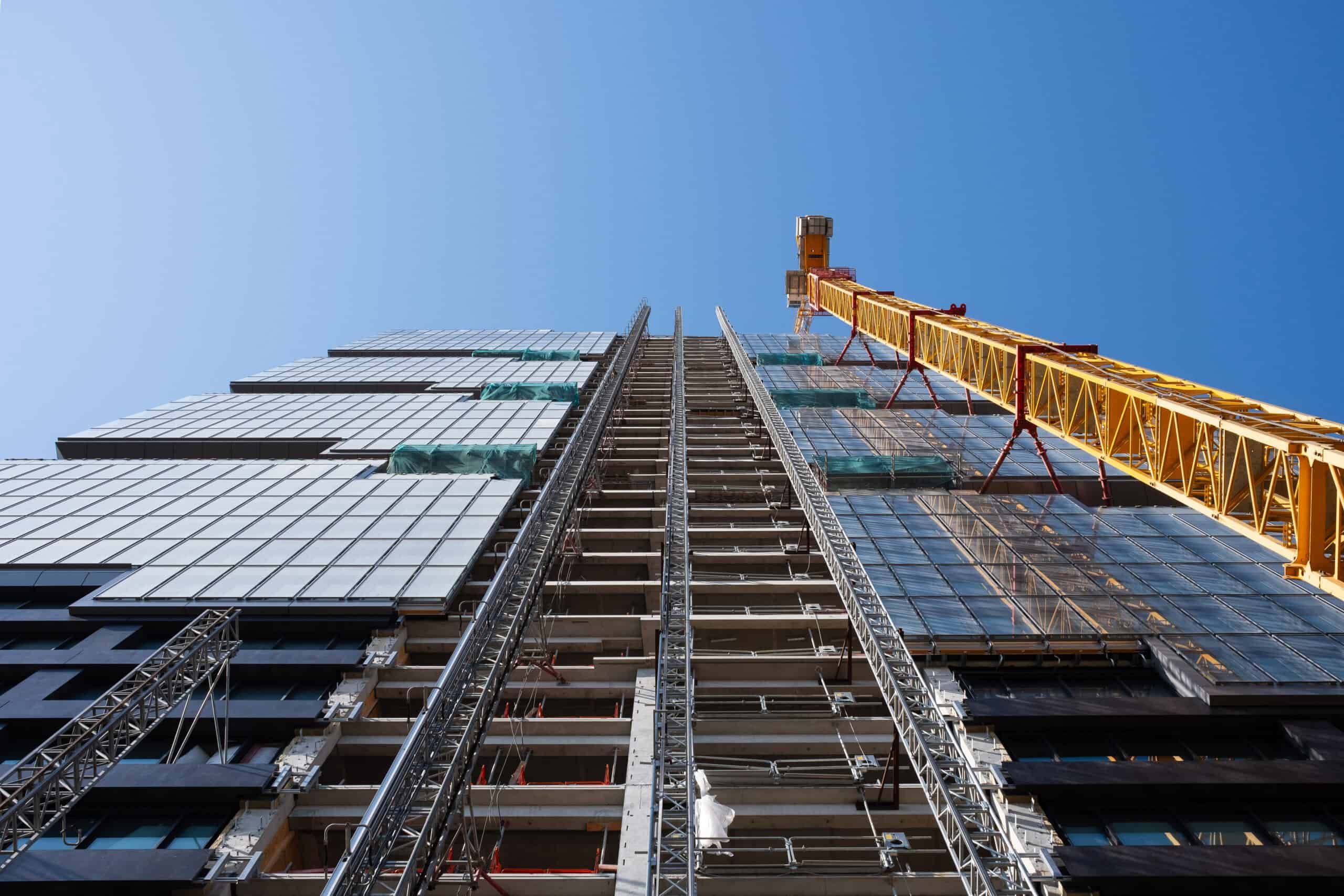 Looking up at the construction site of a high-rise building with a yellow crane